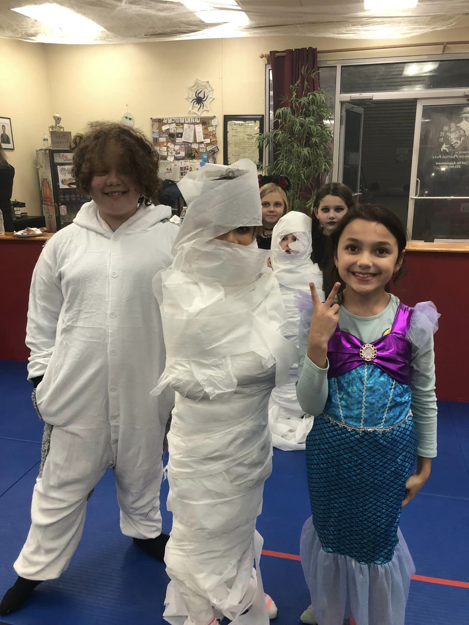 Kids in costumes celebrating at Bellevue Martial Arts School's Halloween party.